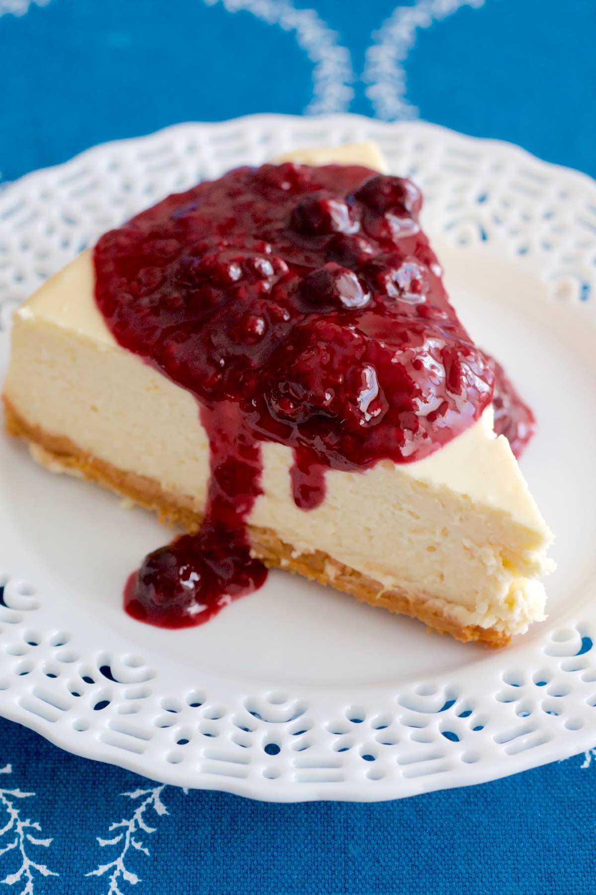 A slice of Classic Cheesecake Mixed Berries Sauce on a plate.