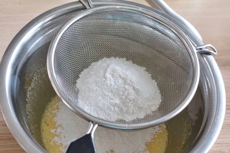 sifting flour over the bowl of egg mixture