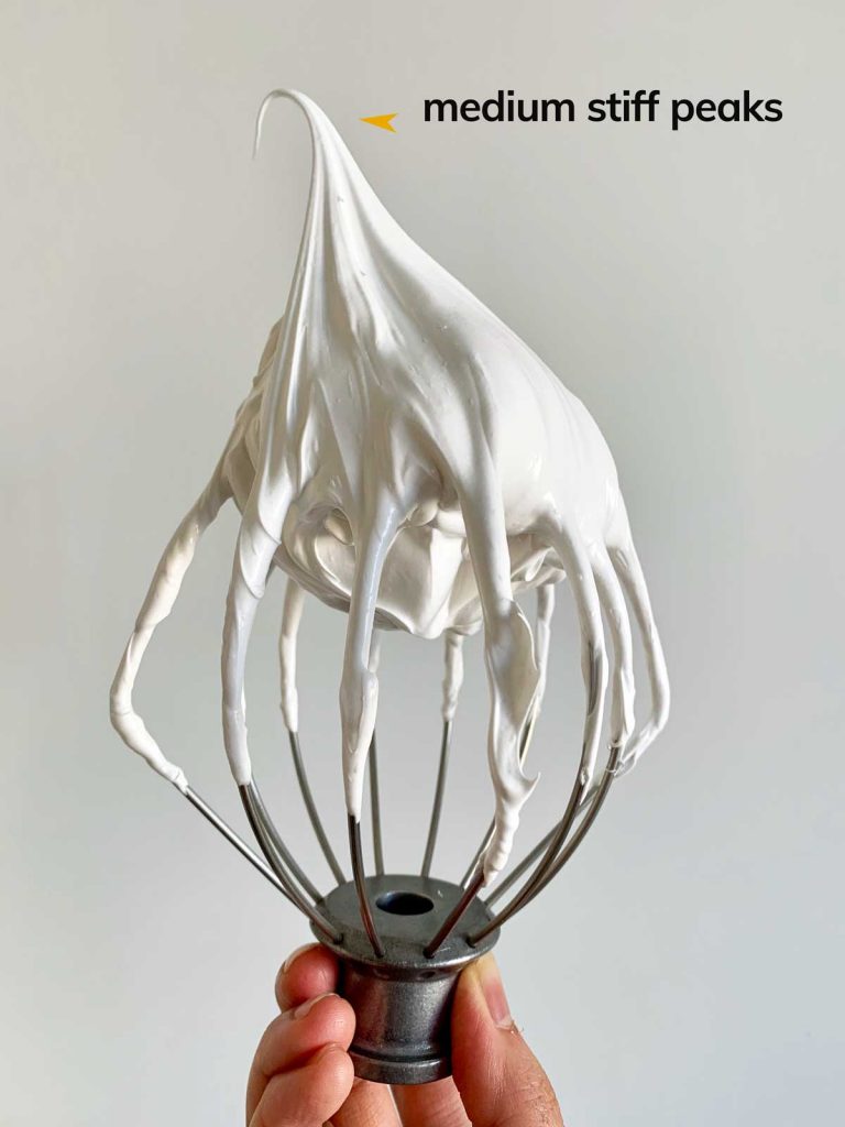 A whisk attachment with whipped egg whites at medium-high speed