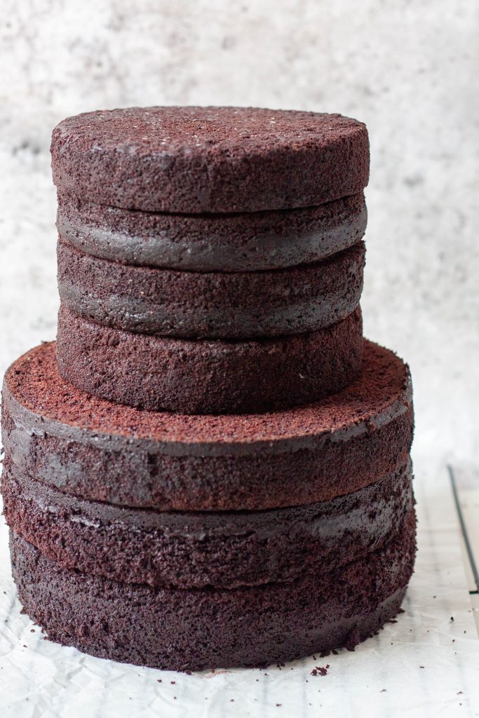 Multiple layers 6-inch and 8-inch of moist and sturdy chocolate cake stacked in two tiers, with a deep chocolate color and even, clean edges.