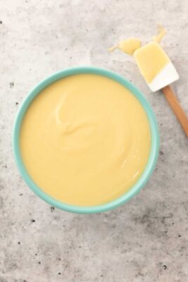 pastry cream in a blue bowl with white spatula on the side