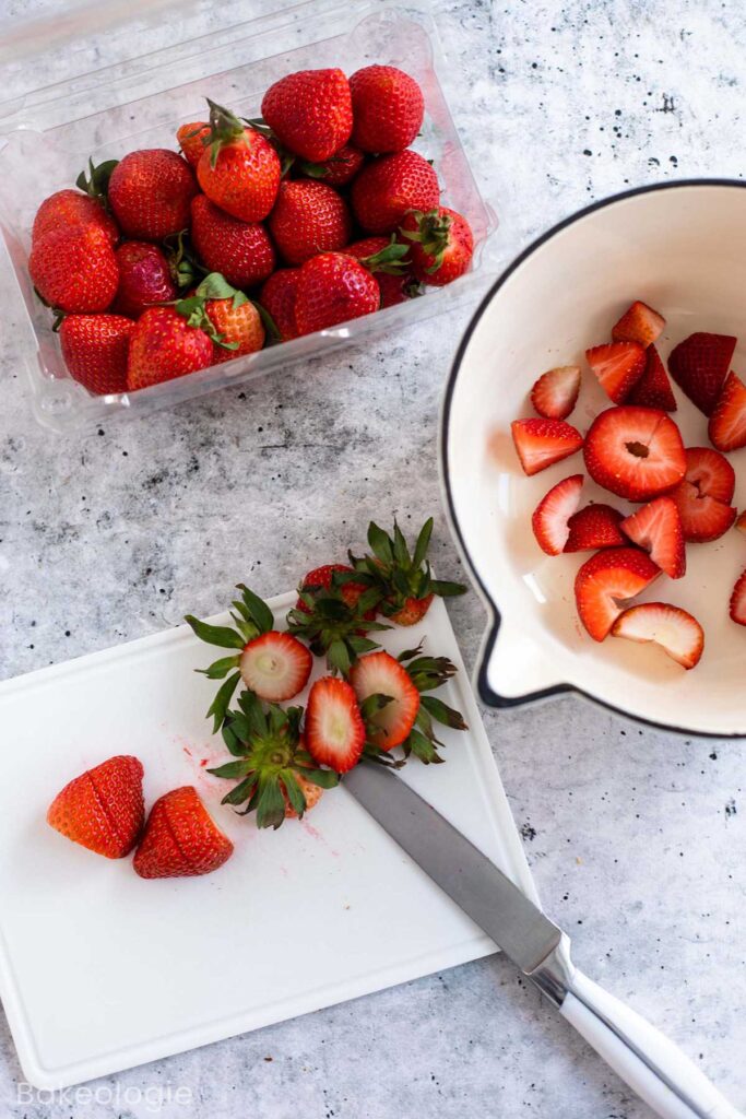 slicing fresh strawberries on a white chopping board