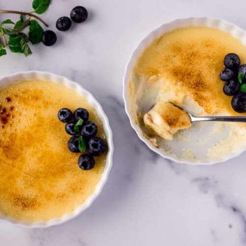 creme brulee in two ramekins with fresh blueberries on top