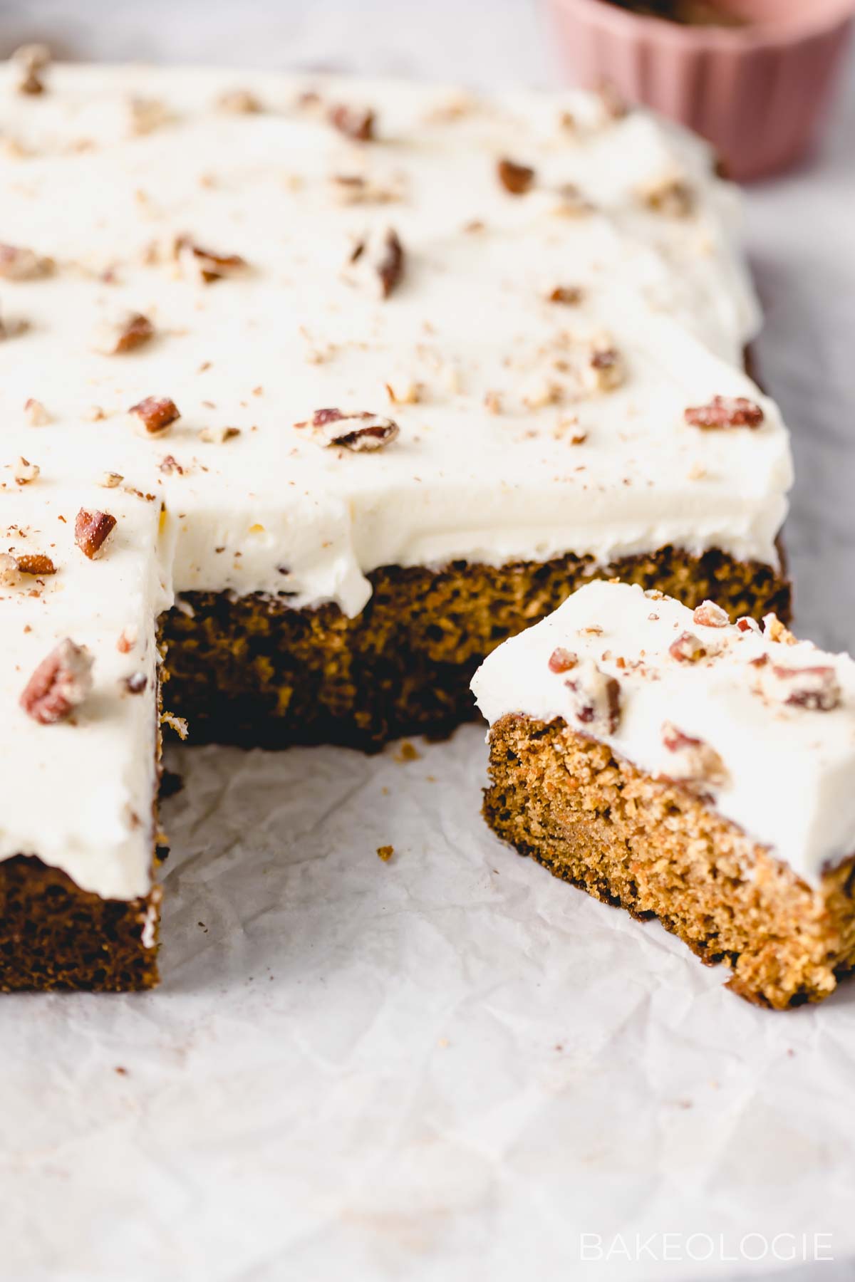a slice of carrot snack cake with cream cheese frosting and chopped pecans