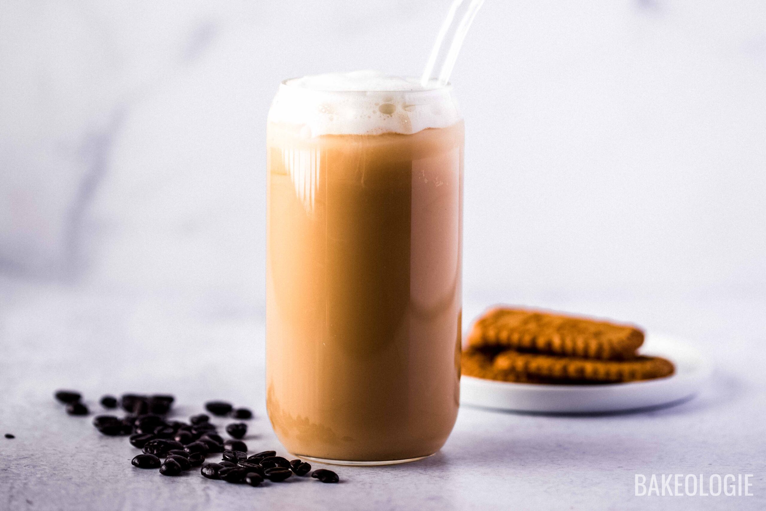 iced coffee topped with vanilla sweet cream cold foam and with cookies behind