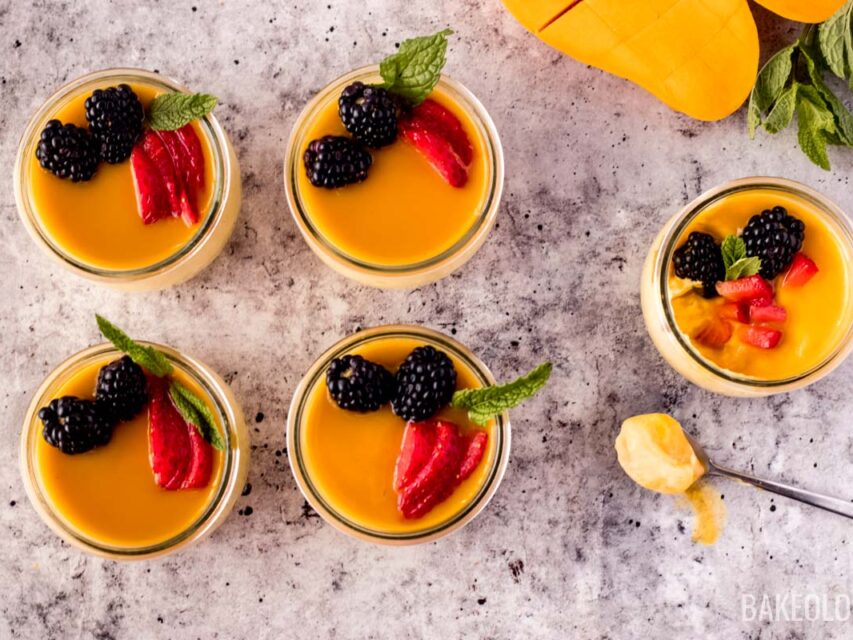 mango mousse served in individual glass containers with a spoon of creamy mango mousse