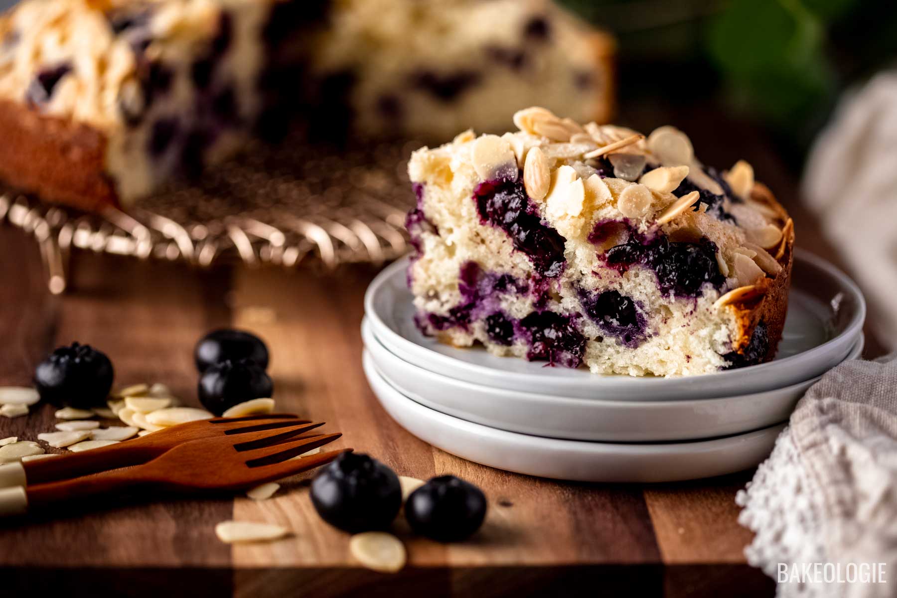 A close-up view of a sliced blueberry cake on a stack of small white plates - landscape photo