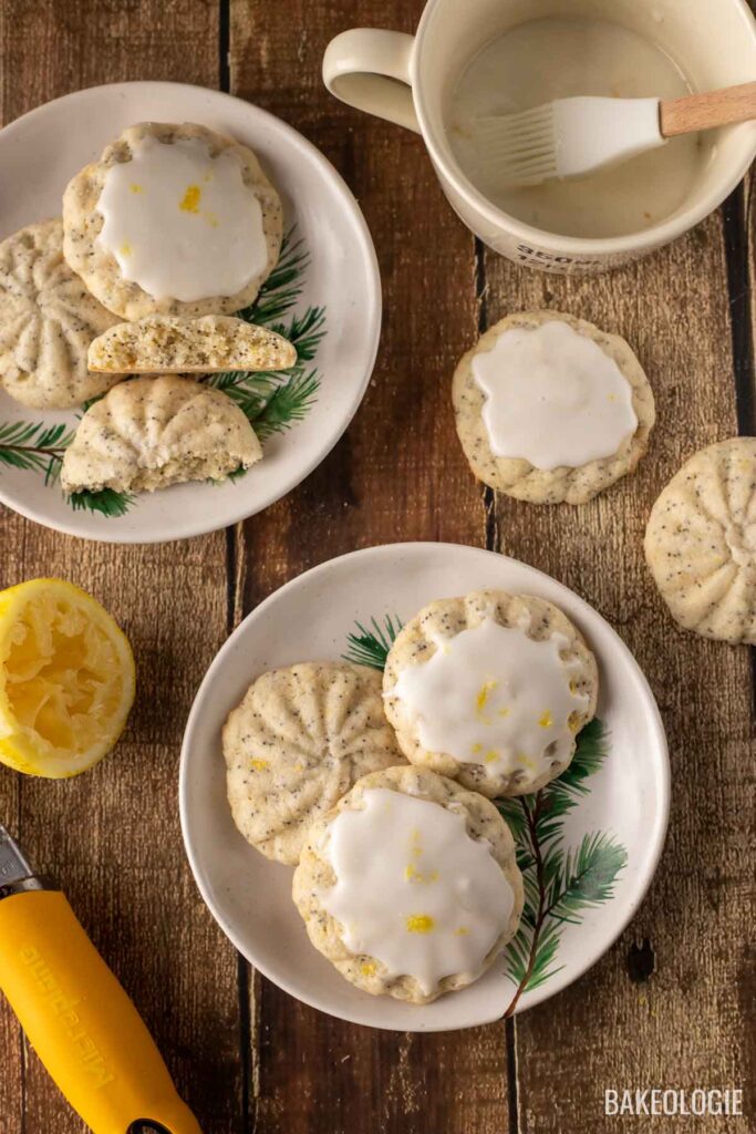 Lemon poppy seed cookies with a glaze, served on festive plates with pine designs, placed on a rustic wooden surface.