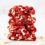 a stack of red velvet cookies cut in half showing the gooey, melty white chocolate.