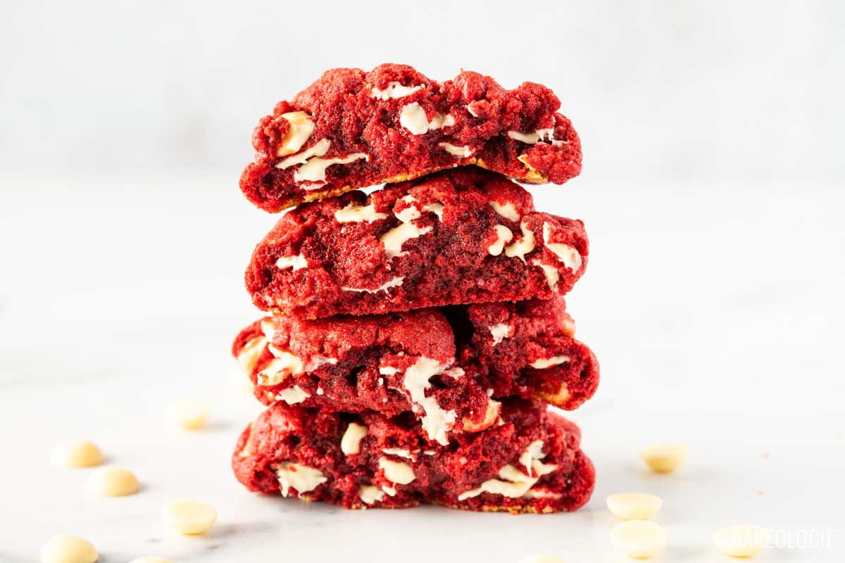 a stack of red velvet cookies cut in half showing the gooey, melty white chocolate.