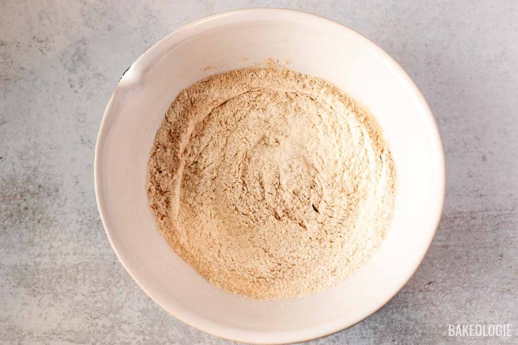 A bowl of dry ingredients, including flour, ready to be mixed together for the carrot cake batter.