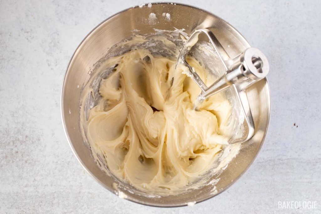 A close-up of a smooth, finished cream cheese glaze in a mixing bowl, ready to be drizzled over the carrot Bundt cake.