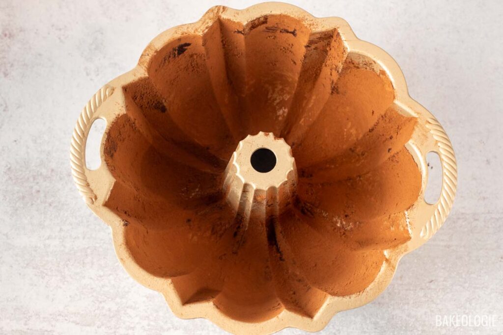 An overhead view of a Bundt pan greased with butter and dusted with cocoa powder, ready for the carrot cake batter.