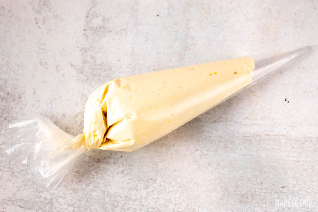 A piping bag filled with cheesecake filling, sealed at the top, ready for use in the carrot Bundt cake recipe.