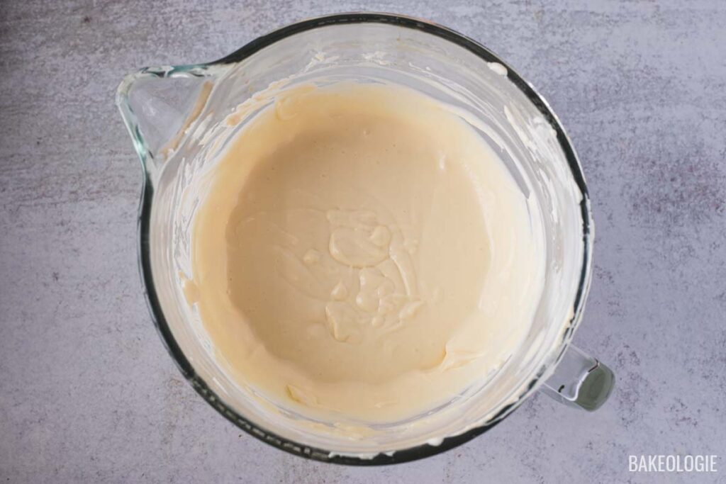 Glass mixing bowl filled with smooth, creamy cheesecake batter for Blueberry Crumble Cheesecake Bars, ready for the next step.
