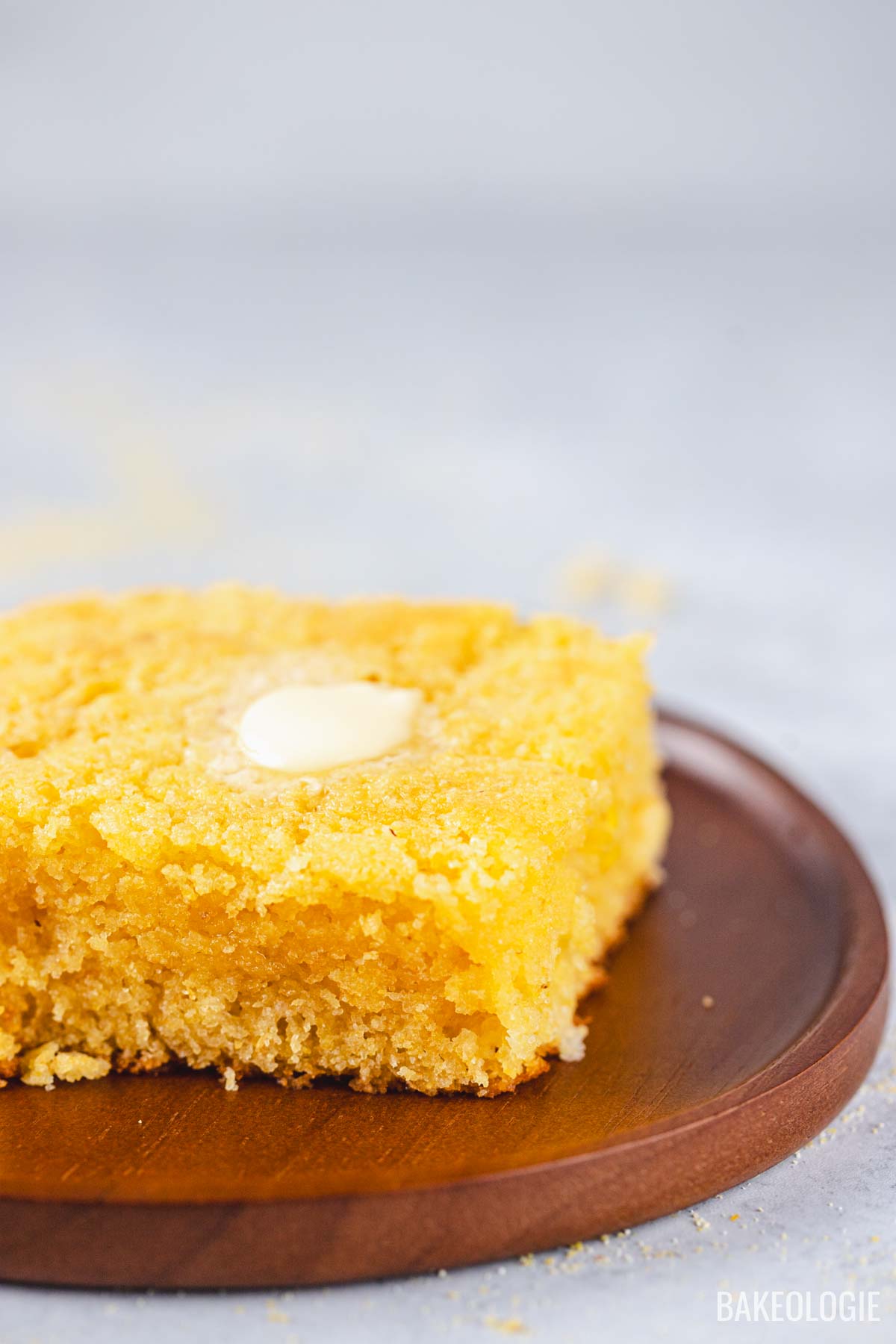 Close-up of cornbread slice with moist tender crumb and melted butter on top.