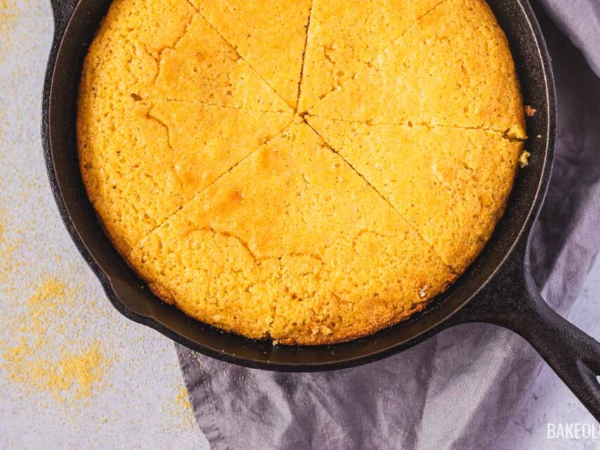 Cast iron skillet cornbread recipe with golden brown crust, sliced into wedges showing crispy edges and tender crumb.