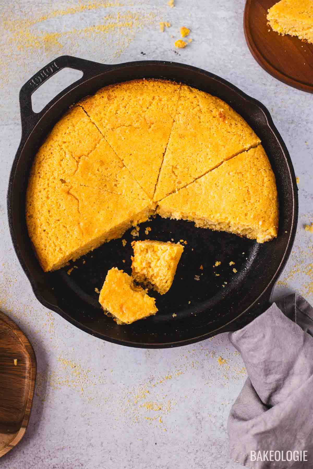 Cast iron skillet cornbread with crispy edges and moist tender crumb, sliced into wedges.