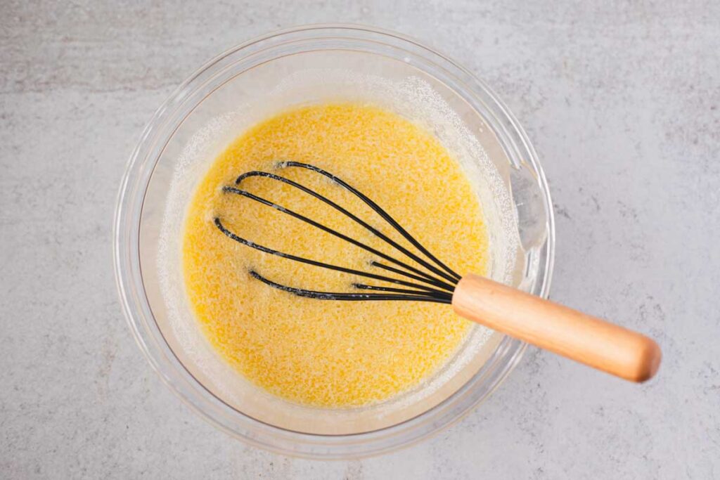 Eggs, buttermilk, milk, melted butter, and honey whisked together in a glass bowl for easy skillet cornbread.