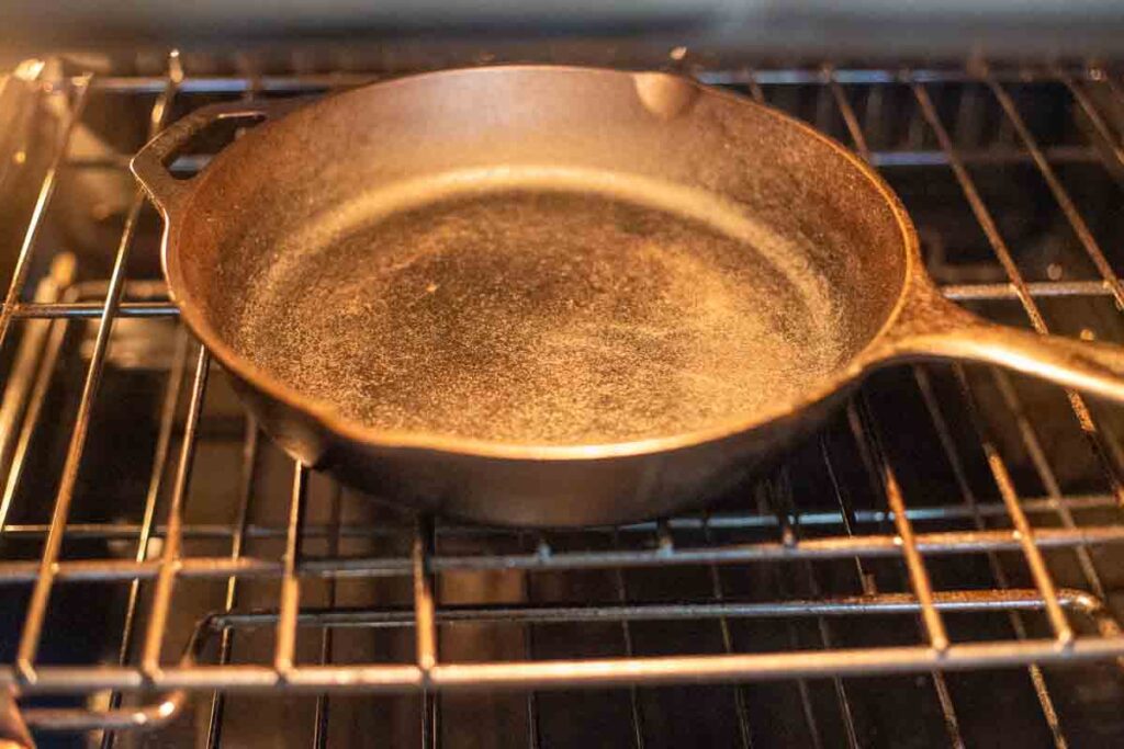 Cast iron skillet preheating in the oven at 425°F to make skillet cornbread with crispy edges.