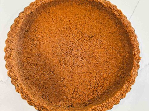 Baked graham cracker crust in a fluted 9-inch tart pan with golden brown edges and a smooth, even crumb base.
