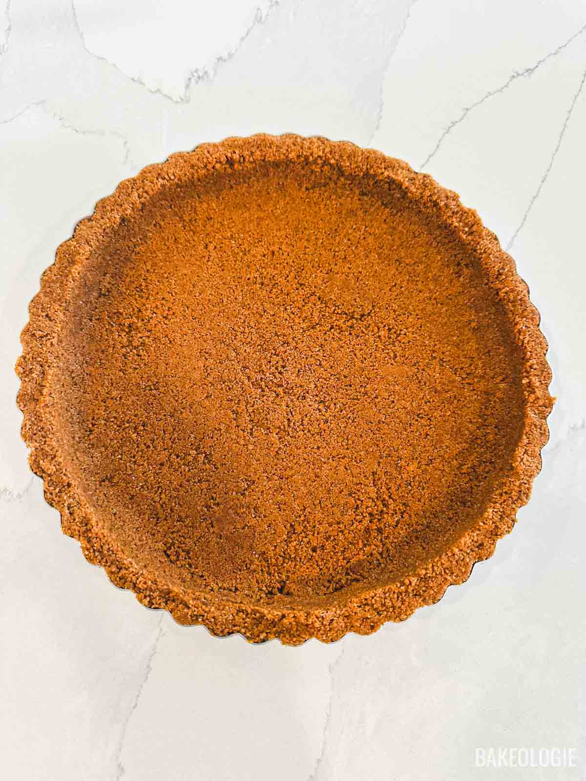 Baked graham cracker crust in a fluted 9-inch tart pan with golden brown edges and a smooth, even crumb base.