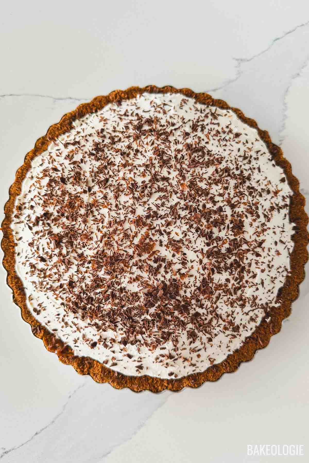 Homemade Banoffee Pie topped with whipped cream and chocolate shavings in a graham cracker crust
