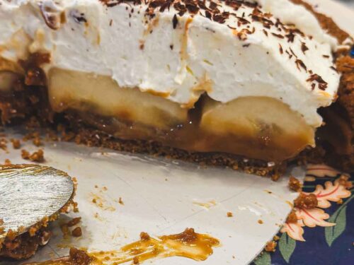 Close-up of Banoffee Pie slice showing caramel layer, sliced bananas, whipped cream, and chocolate shavings