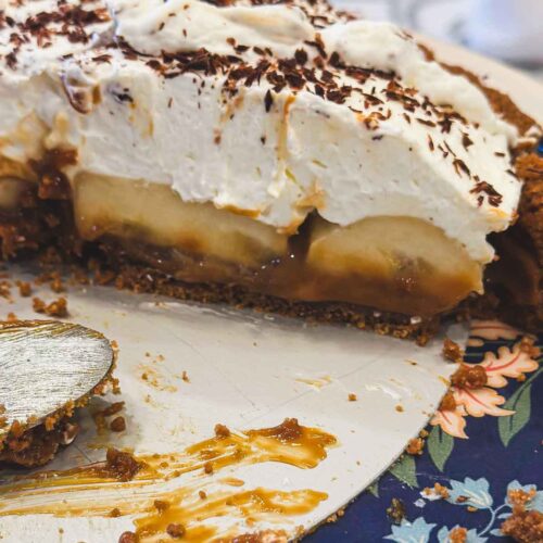 Close-up of Banoffee Pie slice showing caramel layer, sliced bananas, whipped cream, and chocolate shavings