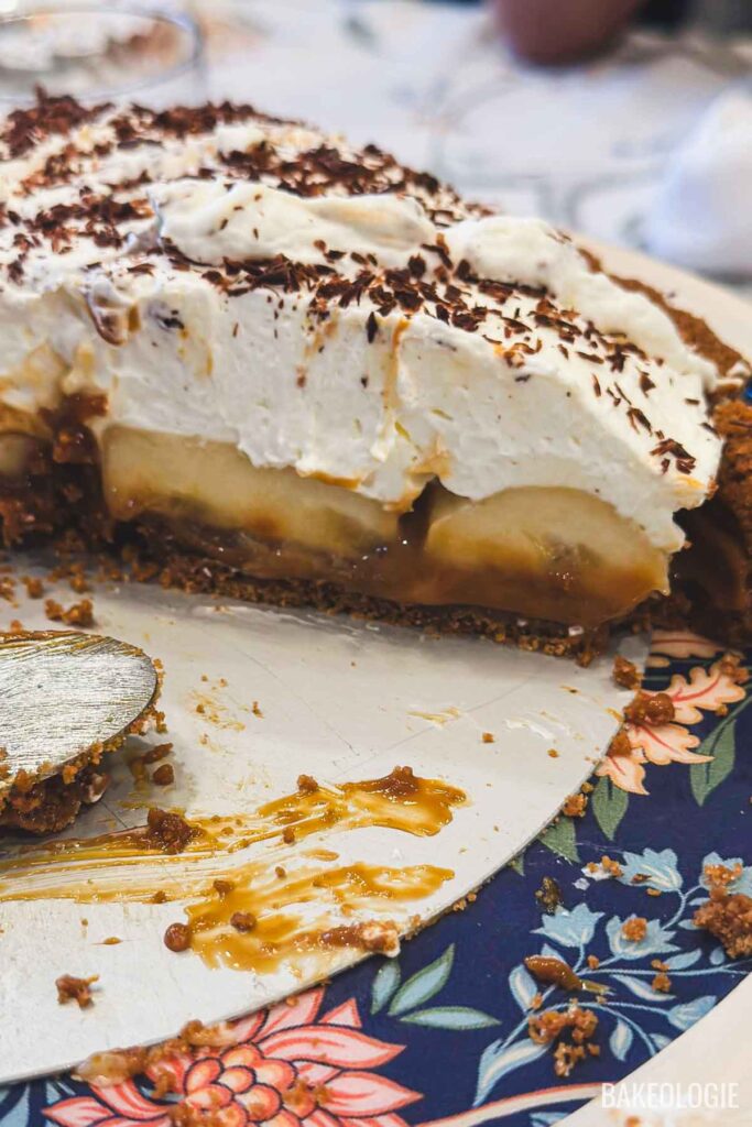 Close-up of Banoffee Pie slice showing caramel layer, sliced bananas, whipped cream, and chocolate shavings