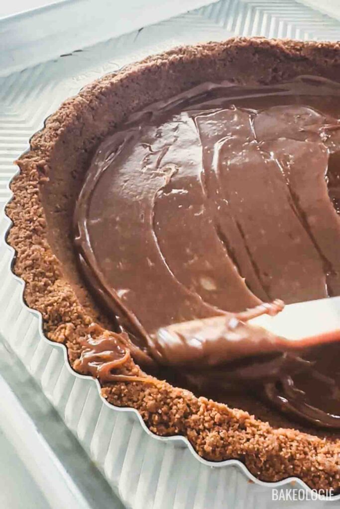 Spreading dulce de leche over the graham cracker crust for Banoffee Pie