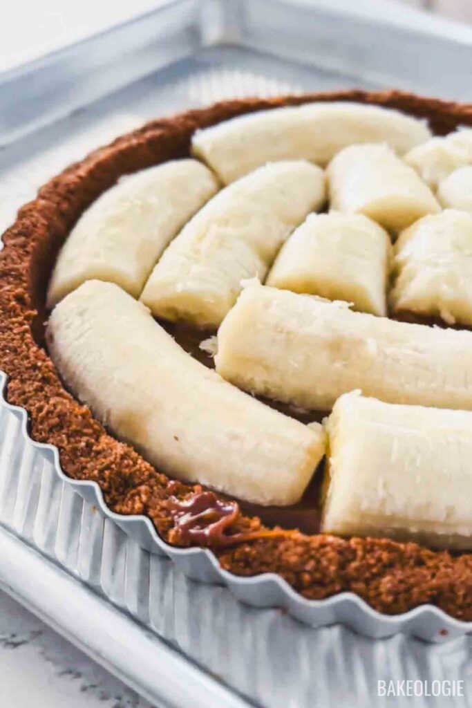 Layering sliced bananas on top of dulce de leche in Banoffee Pie crust