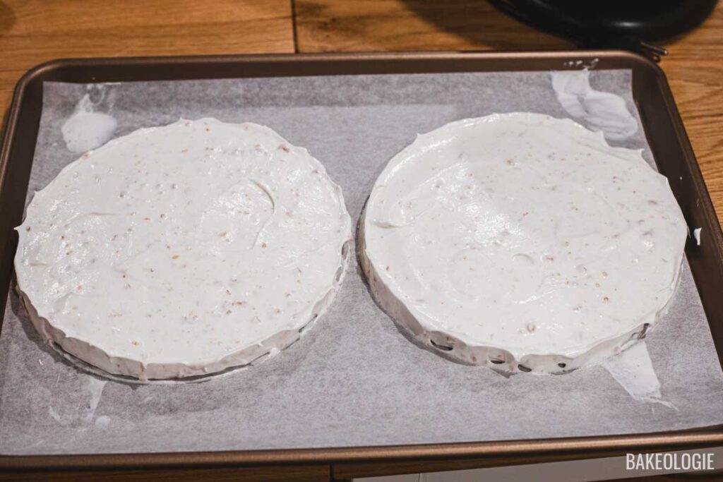 Meringue spread into two 8-inch circles on a parchment-lined baking sheet, ready for baking.