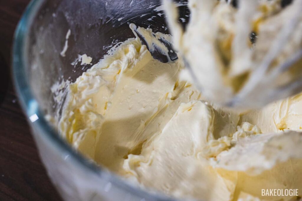 A bowl of smooth, creamy buttercream being mixed, showing its thick and fluffy texture.