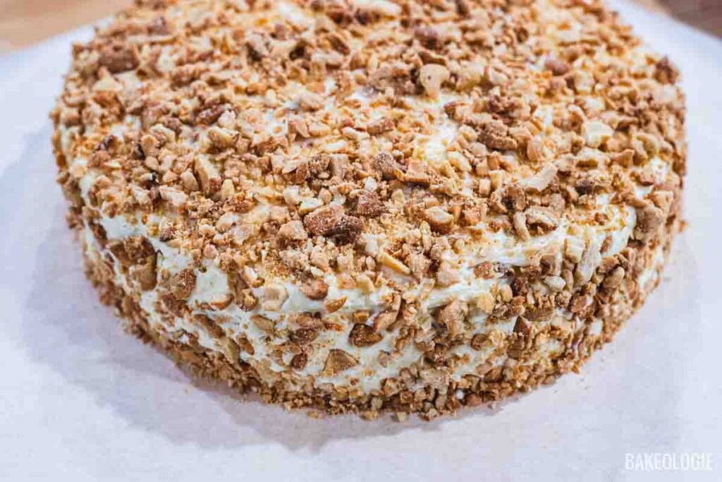 A fully assembled Sans Rival cake coated with crushed toasted cashews on all sides.