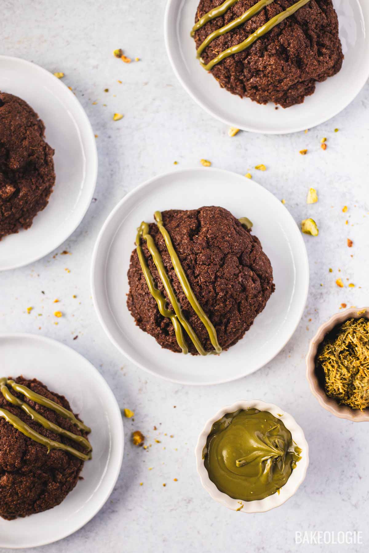 Dubai chocolate cookies drizzled with pistachio cream on white plates, featuring a rich chocolate exterior and Middle Eastern–inspired flavors.