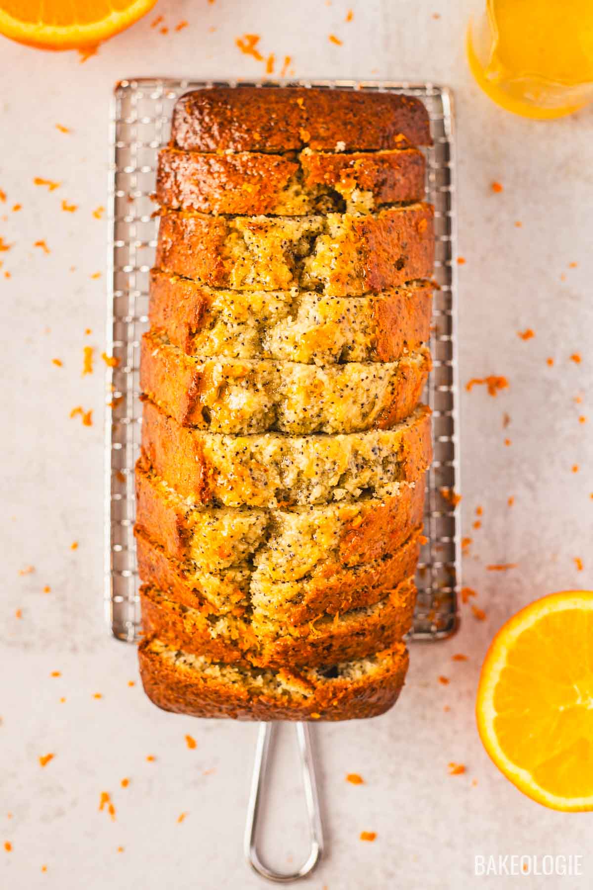 Sliced orange poppyseed loaf cake on a wire rack with orange glaze
