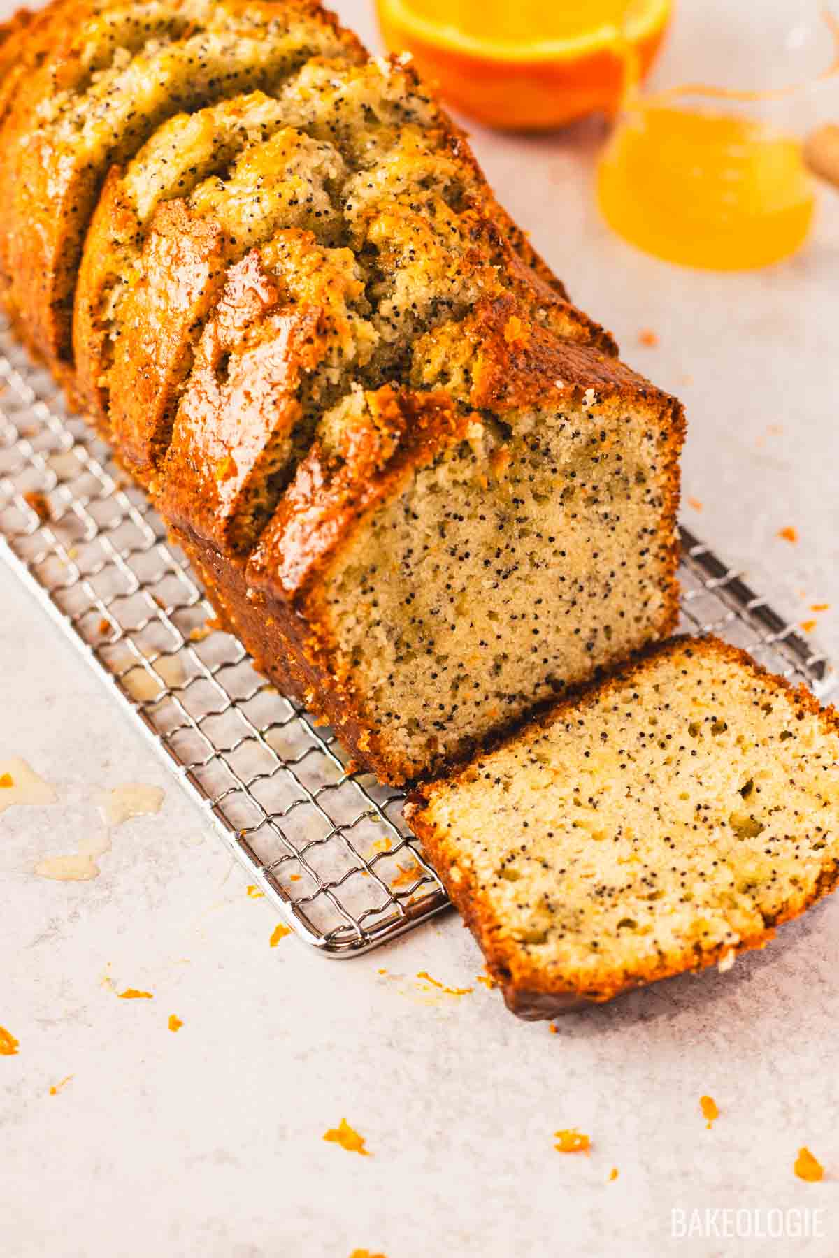 Orange poppyseed loaf cake sliced on a wire rack with orange glaze