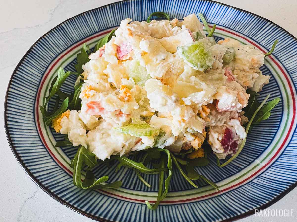 Close-up of Korean potato salad with chunks of potato, apple, cucumber, and carrot on a bed of greens