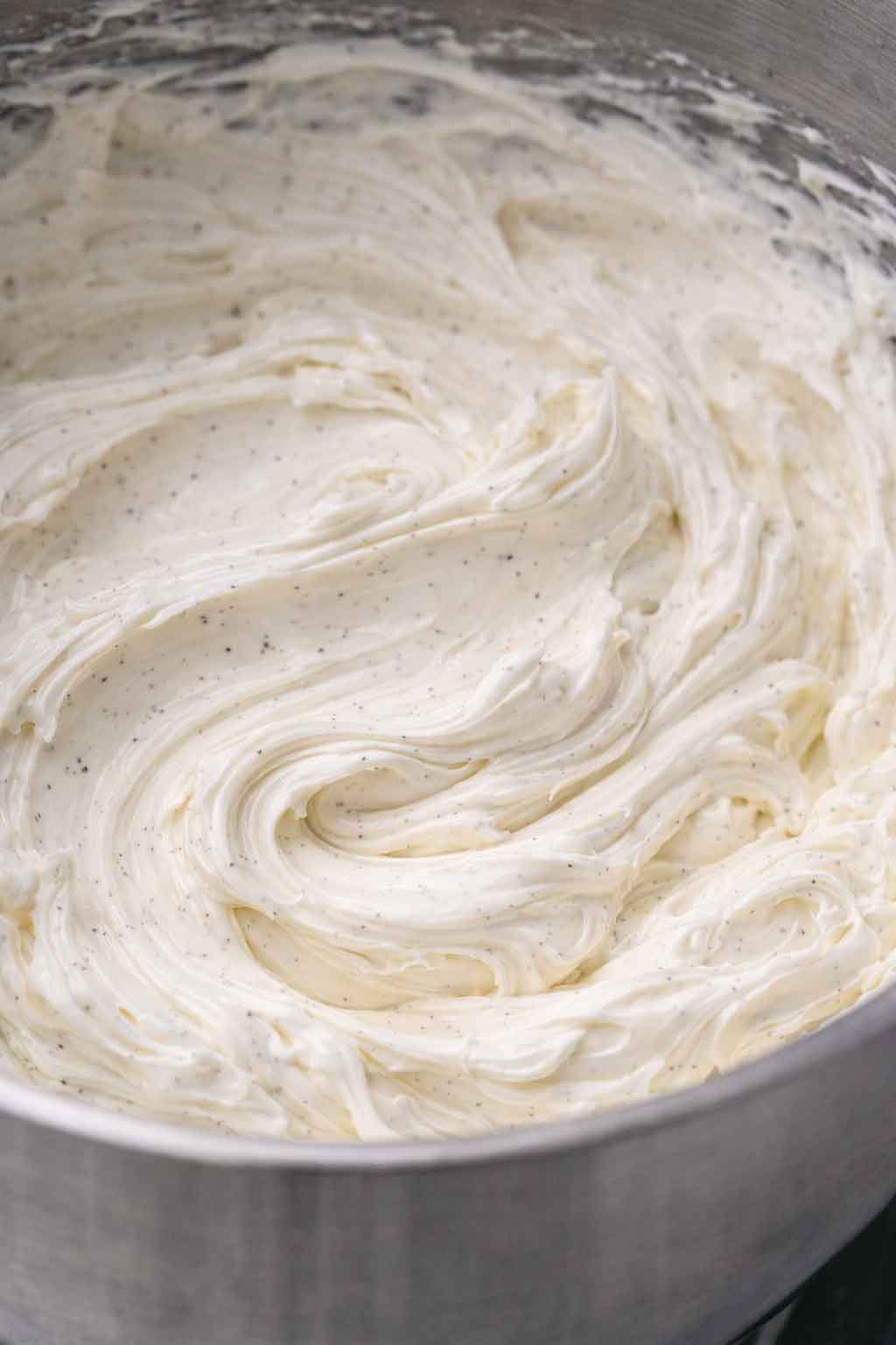 Close-up of silky smooth Swiss meringue buttercream with vanilla bean flecks in a mixing bowl