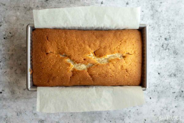 Freshly baked cream cheese pound cake with a golden crust and classic center crack cooling in the loaf pan.