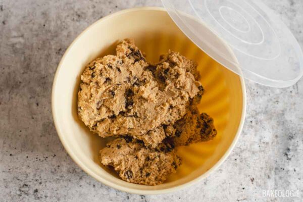 Chocolate chip cookie dough transferred to a container for chilling.