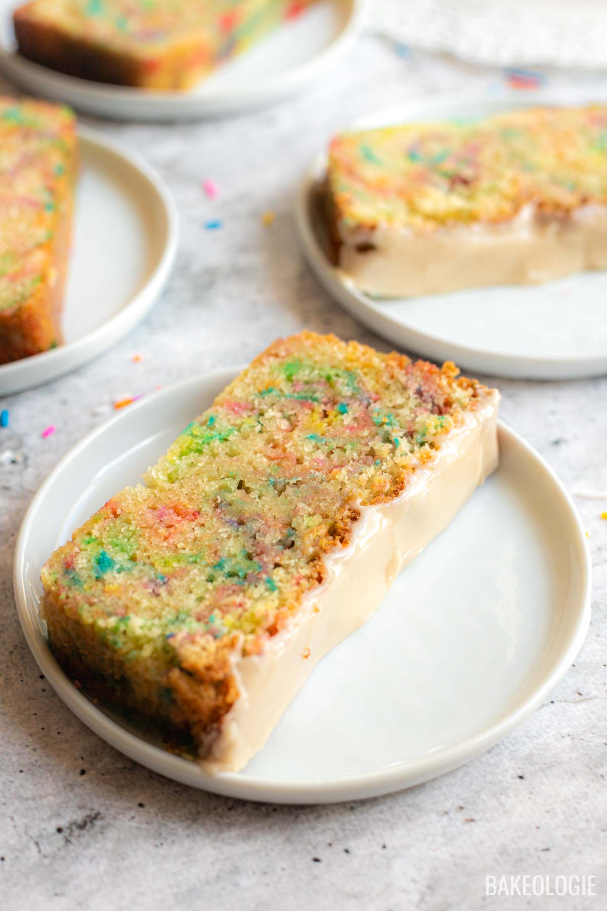 Close-up of Funfetti Sour Cream Pound Cake showing its moist crumb, colorful sprinkles, and vanilla glaze.