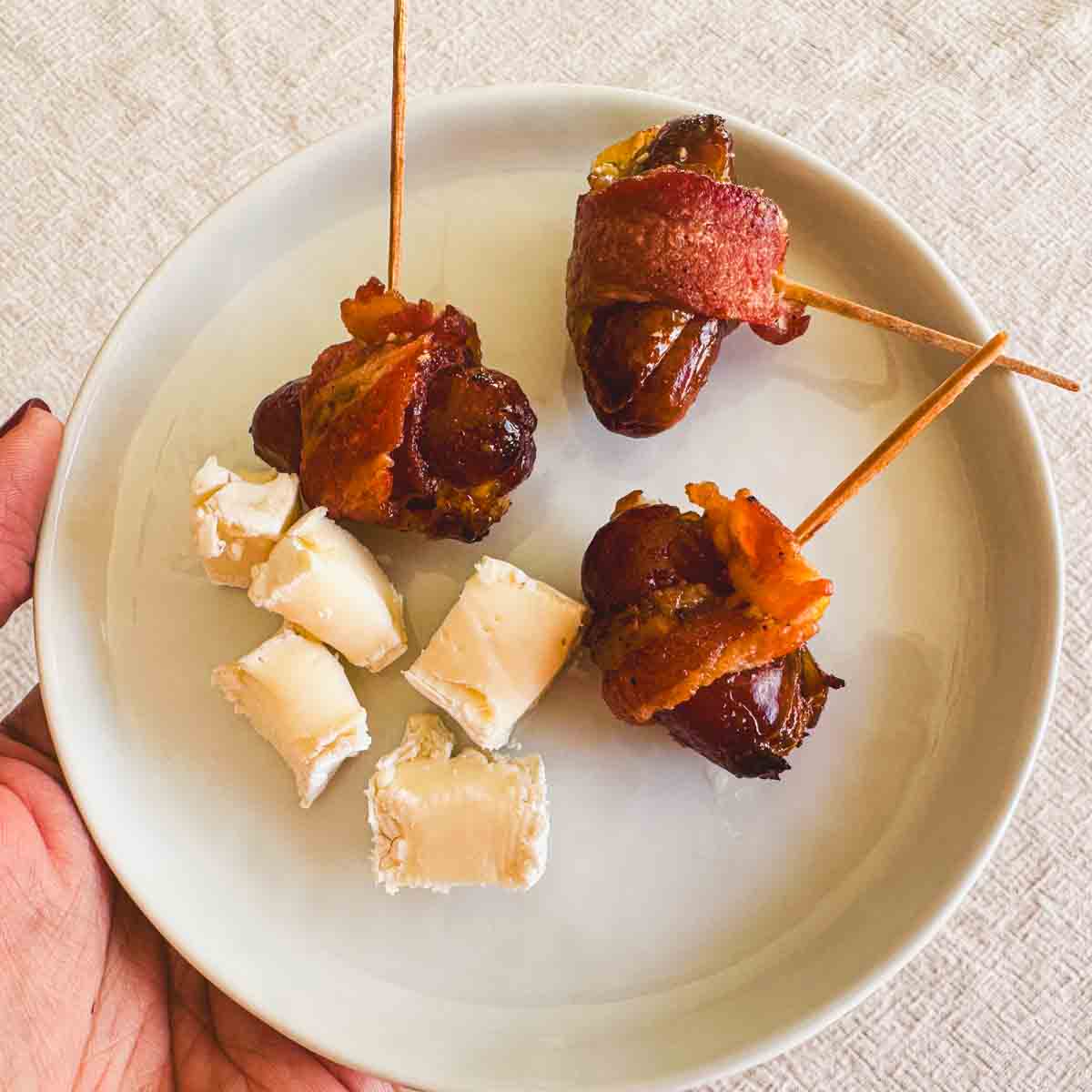 Bacon-wrapped dates with pieces of Brie served on the side