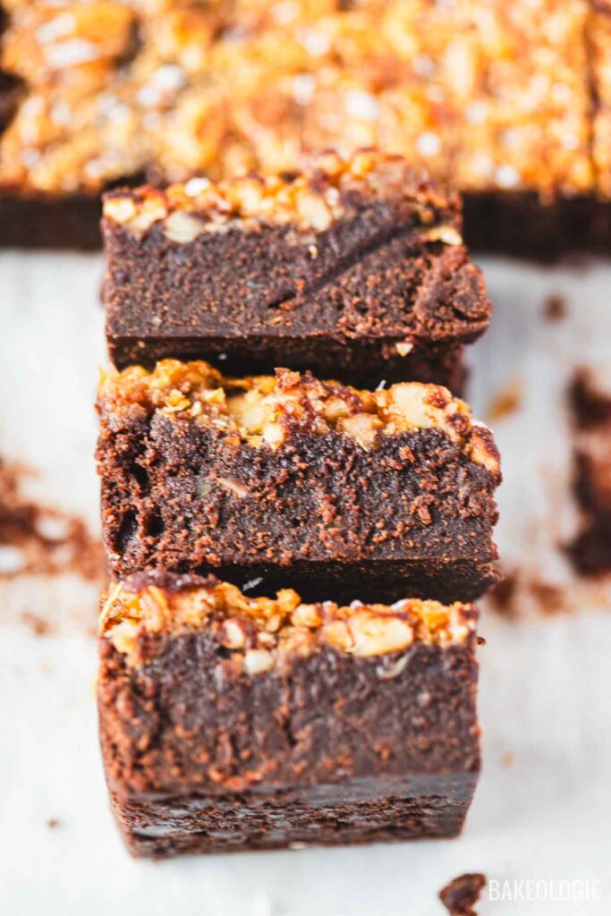 Stacked pecan pie brownies with a sliced slab of brownies in the background.