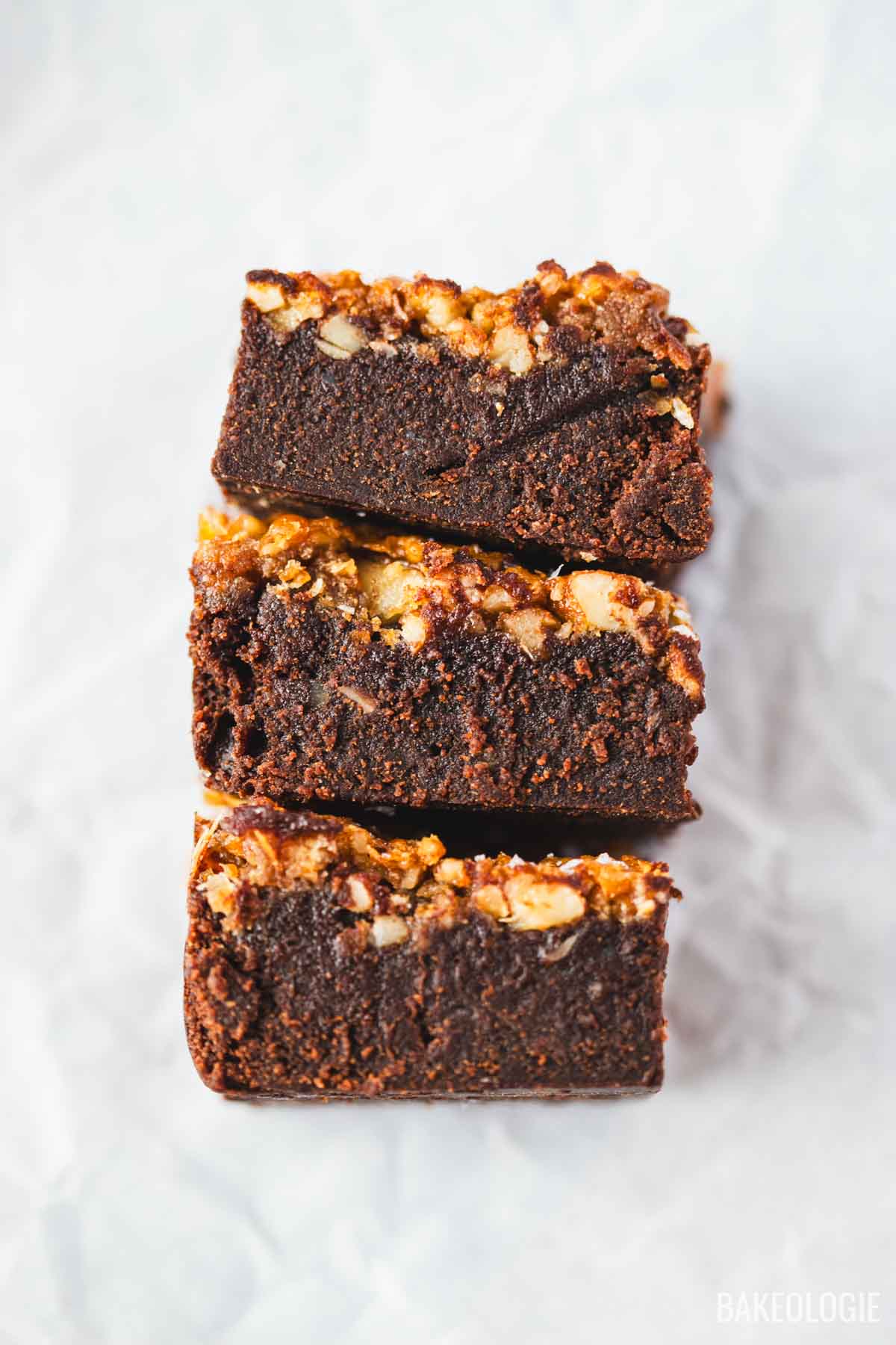 Three stacked pecan pie brownies showing the dark chocolate base and chopped pecan topping.